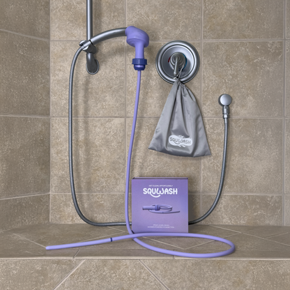 Patented portable shower douche and enema attached to shower head with packaging on a tiled bathroom bench, featuring the brand 'Squwash'.
